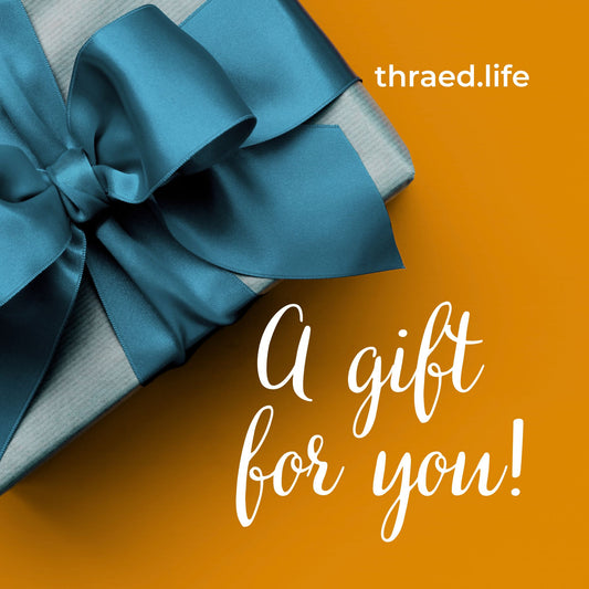 A gift box with a blue bow on an orange background, with the text 'A gift for you! thraed.life' indicating a present from the brand. Gift card.