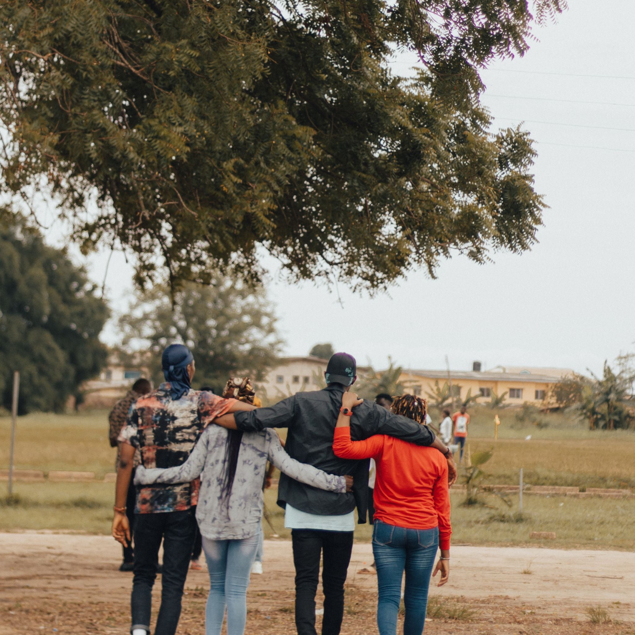 Group of people walking together on a path with trees and buildings in the background.